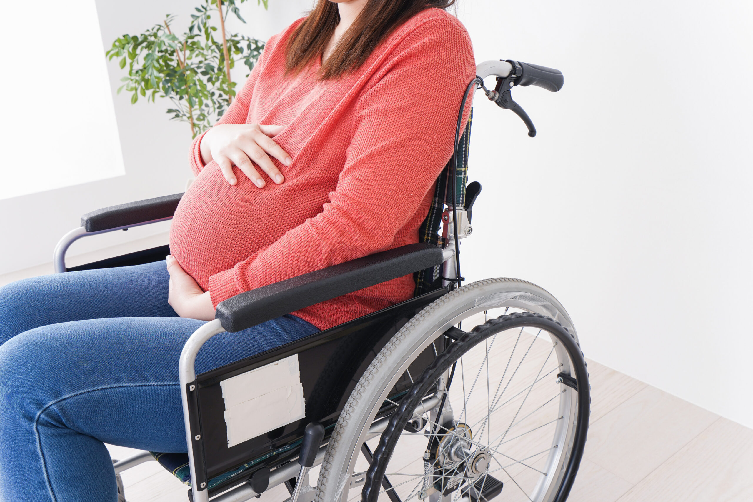 Femme enceinte en fauteuil roulant, les mains sur le ventre
