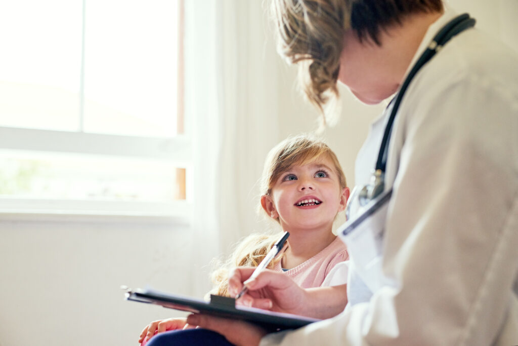 Une pédiatre échange avec une petite fille souriante lors d’une consultation de suivi
